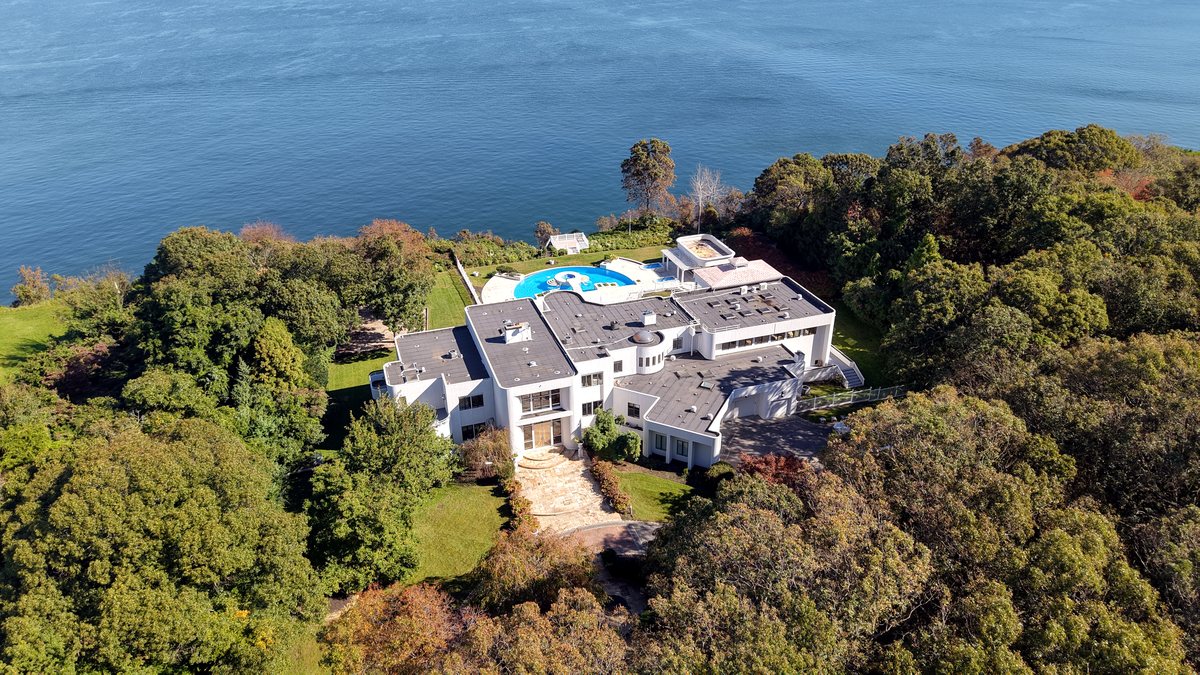 Aerial view of 157 Cliff Road: the house and grounds among the trees, on the bluff above Long Island Sound