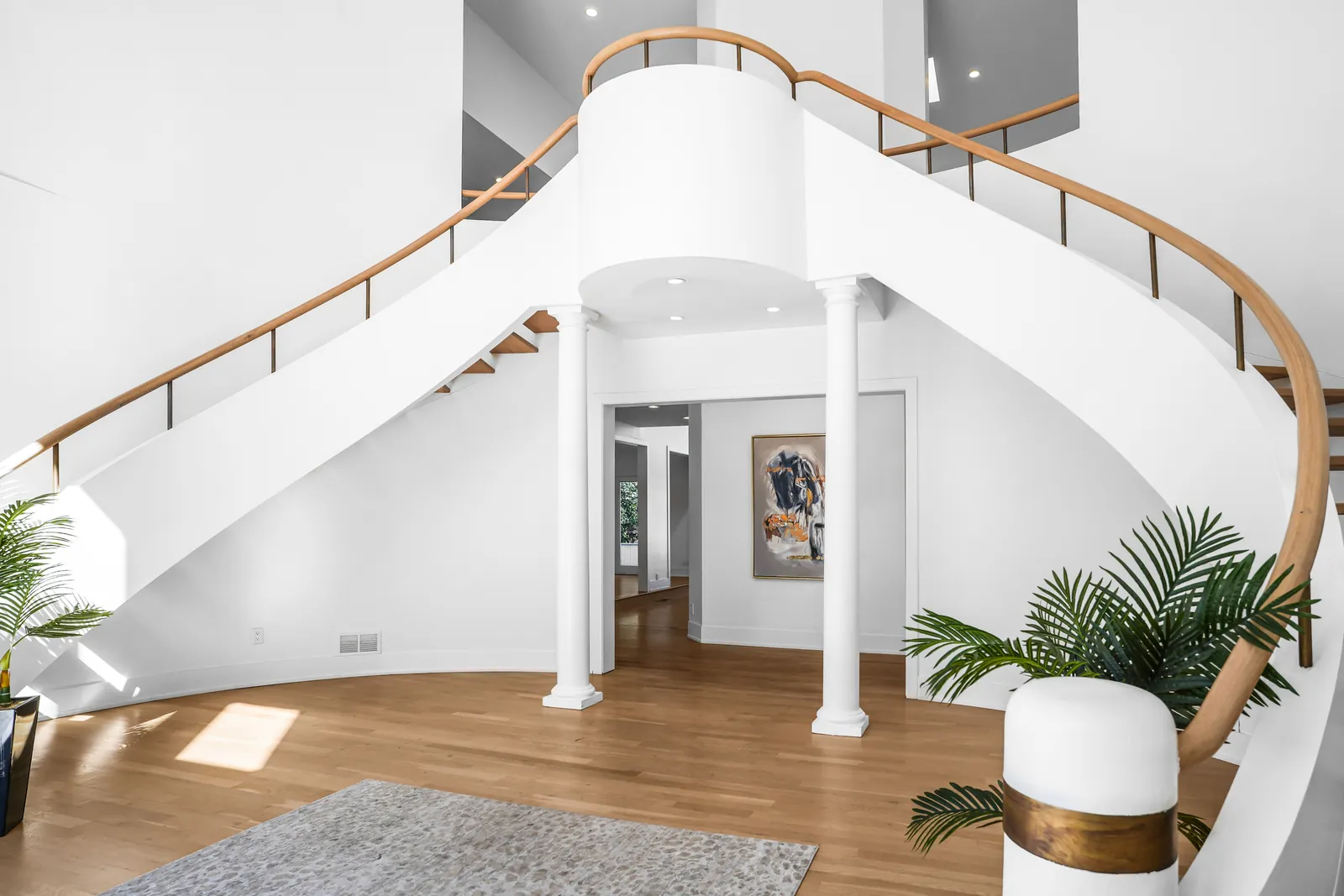Curved foyer stair with a wood handrail and white columns