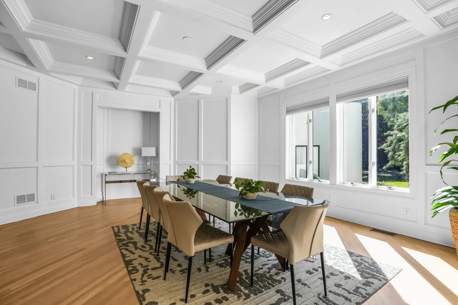 Dining room under a coffered ceiling, with windows to the trees